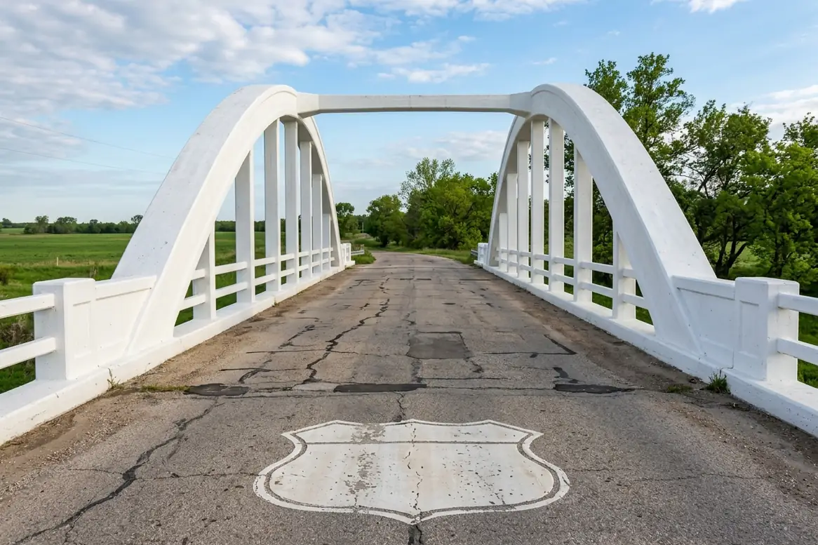 Cracked deck of the white Brush Creek Rainbow Bridge near Riverton, Kansas, with a road shield