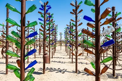 Glass bottles in green, blue and amber on rusty poles at Elmer's Bottle Tree Ranch, California