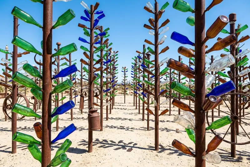 Glass bottles in green, blue and amber on rusty poles at Elmer's Bottle Tree Ranch, California