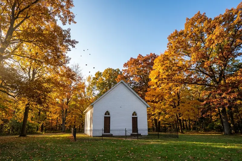 Funks Grove Chapel, a small white clapboard church in Illinois, under orange autumn trees